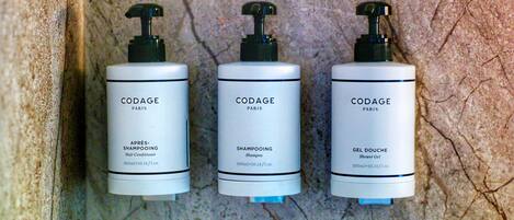 Tres botellas de CODAGE Paris sobre una pared con textura.