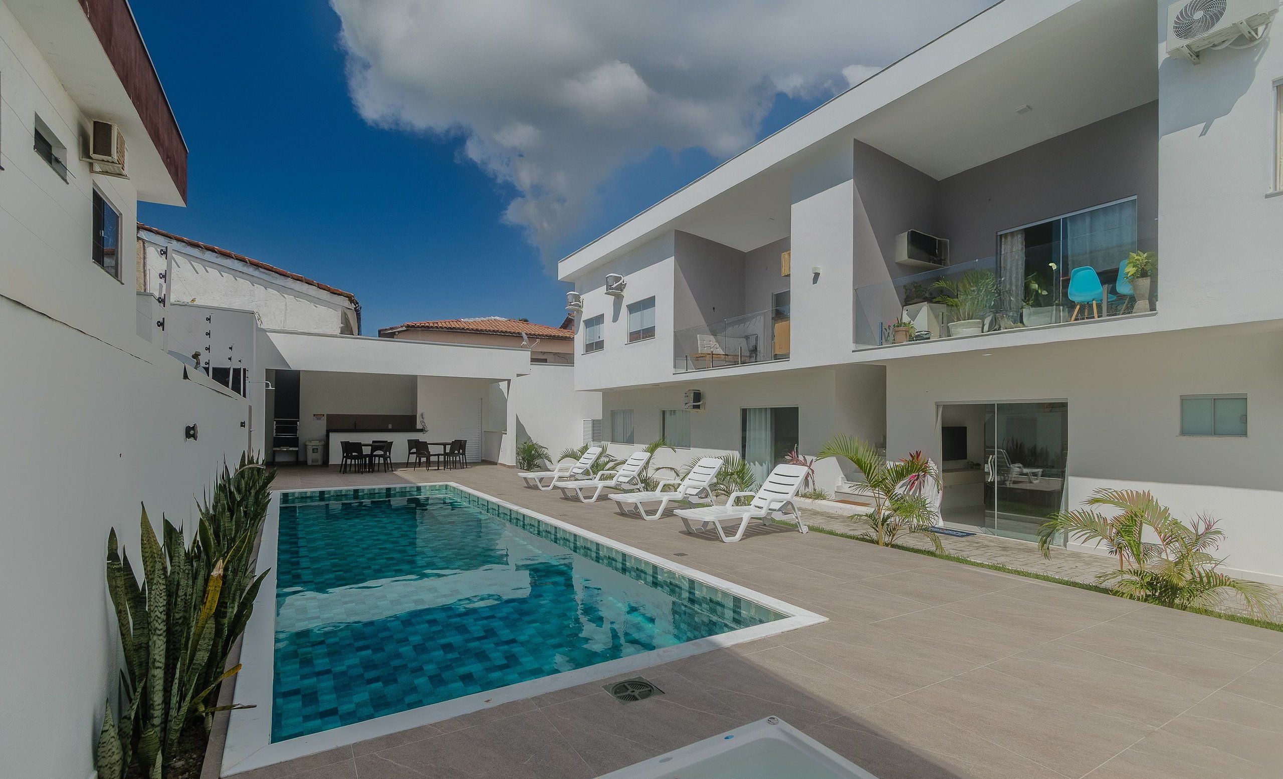 A modern outdoor pool area with lounge chairs, a bar, and a dining area.