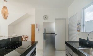 A modern kitchen with a stainless steel refrigerator, black countertops, and a built-in oven. - 4-bedroom Apart in Condominium With Pool Vif0104 (Porto Seguro)