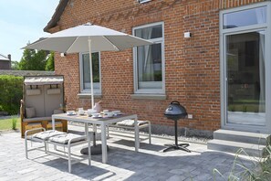 Une terrasse avec une table, des chaises et un grand parasol.