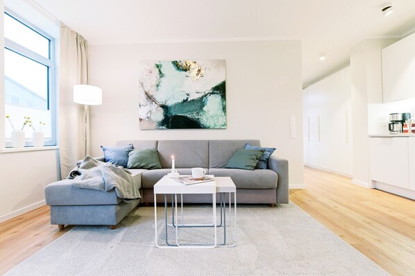 Un salon moderne avec un canapé gris, une table basse blanche et un grand tableau abstrait accroché au mur.