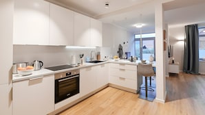 A modern kitchen with white cabinets, a built-in oven, and a dining area with a bar stool.