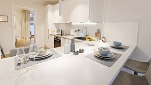 A modern kitchen with white cabinetry, a central island with a sink, and a dining area with a table set for two.