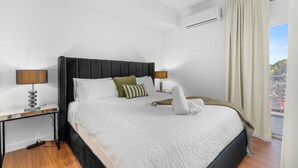Een moderne slaapkamer met een groot bed, twee nachtkastjes, een plafondventilator en uitzicht op het buitengebied.