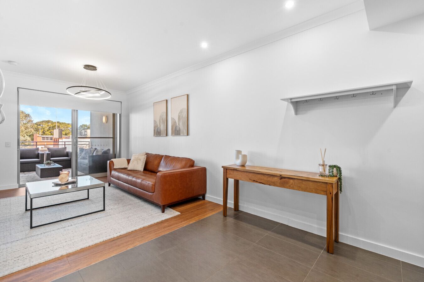Un salon moderne avec un canapé en cuir, une table basse en verre et une console en bois.