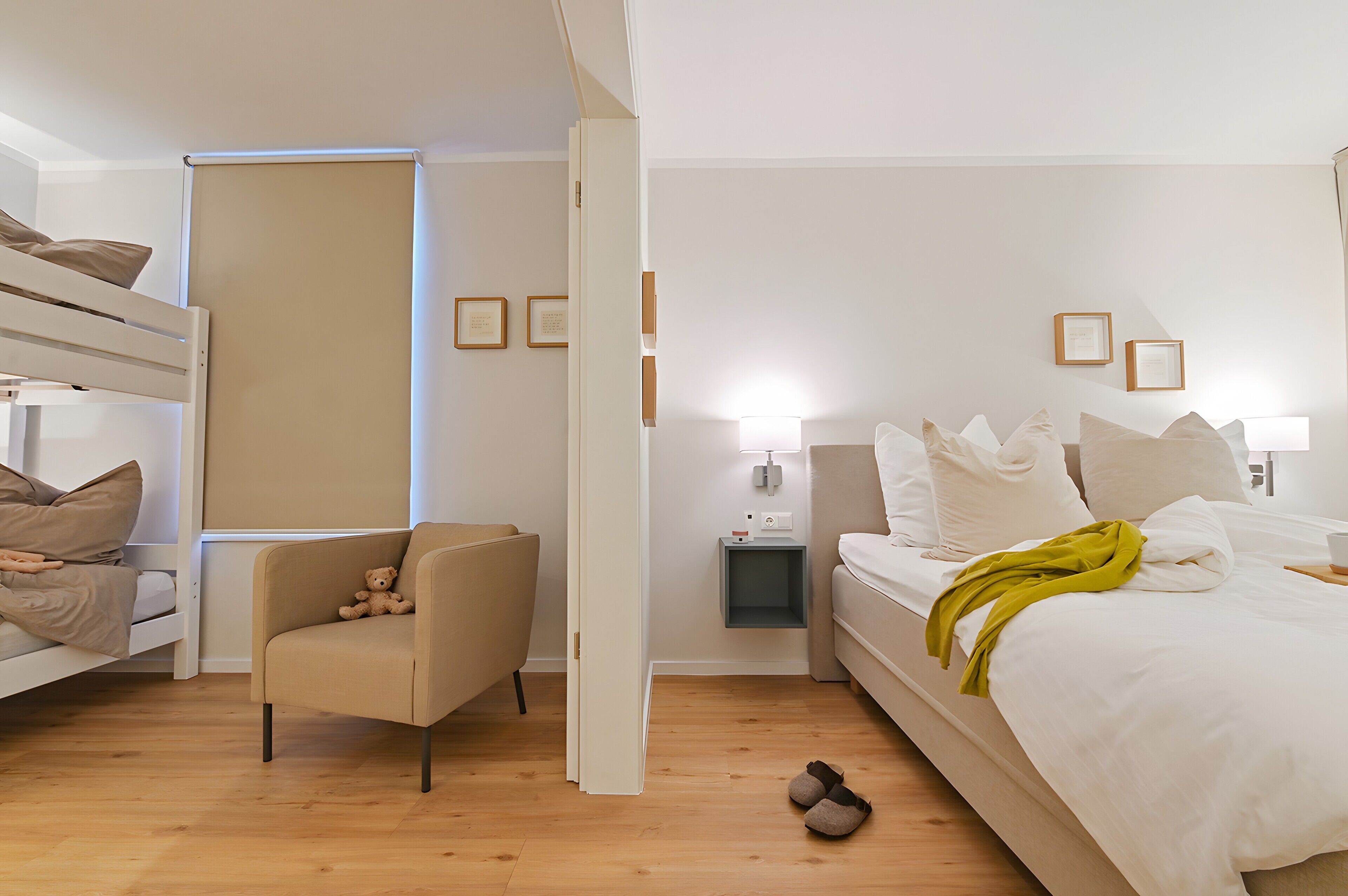 Una habitación con literas, una silla, una mesita de noche, una lámpara y una cama con manta.