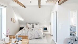 A modern bedroom with a bed, bedside table, and a TV. - Lütter Lünk – Exclusive Loft with Terrace (Fehmarn)