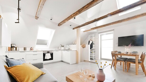 A modern living space with a kitchen, dining area, and a loft bedroom with a skylight. - Lütter Lünk – Exclusive Loft with Terrace (Fehmarn)