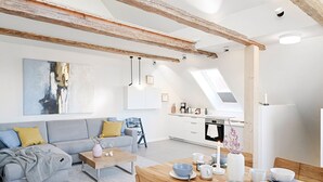 A modern living room with a sofa, coffee table, and dining table set with cups and bowls. - Lütter Lünk – Exclusive Loft with Terrace (Fehmarn)