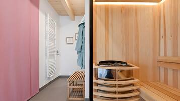 A wooden sauna with a bench, a wooden shelf with stones, and a bench with a towel.