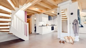 A modern interior with a staircase, kitchen, and a large painting.
