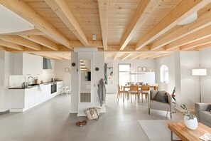 A spacious living area with a kitchen, dining table, and seating. - Kleene Slott – Exclusive Holiday Home with Sauna and Terrace (Fehmarn)