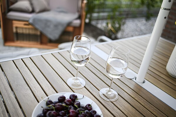 A wooden table with two wine glasses and a plate of grapes.