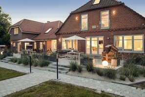 Une maison à deux étages, construite en briques, dotée d’un patio, d’un espace extérieur aménagé pour s’asseoir et d’une entrée bien éclairée.