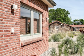 Ein Gebäude aus roten Ziegelsteinen mit einem großen Fenster, einer Satellitenschüssel und einem Holzzaun im Hintergrund.