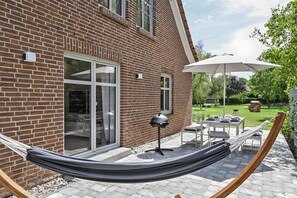 A brick house with a patio, a hammock, and outdoor furniture.