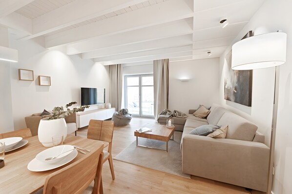 A modern living room with a sofa, coffee table, and dining area.