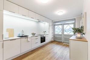A modern kitchen with white cabinets, a built-in oven, and a window with a view.