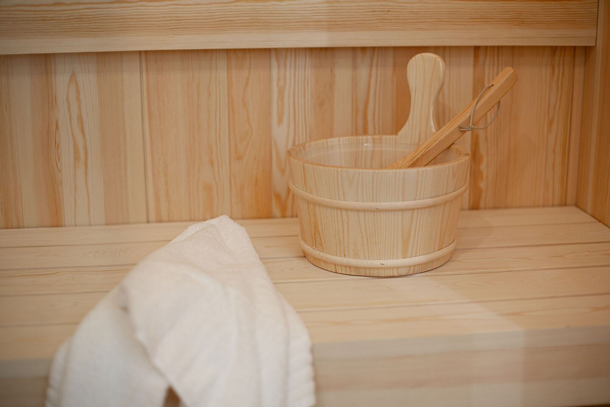 Un sauna en bois, avec un seau en bois et une louche en bois.