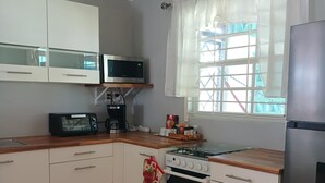 A kitchen with white cabinets, a microwave, a gas stove, and a refrigerator.