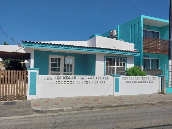 A two-story building with a white and blue facade, a gated entrance, and a visible balcony on the upper floor. - Charming 2-bedroom bungalow in fabulous Willemstad with AC (Willemstad)