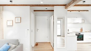 Un interno moderno con soffitto in legno, un divano bianco e un angolo cottura.