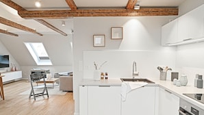 Una cucina moderna con mobili bianchi, un'isola centrale e un lucernario.