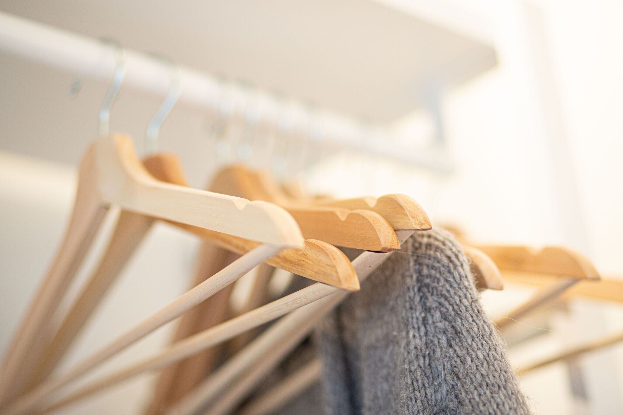 Wooden hangers on a white closet rod.