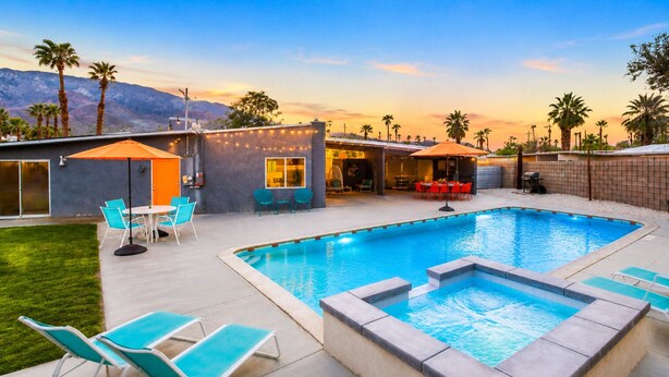 A backyard with a swimming pool, outdoor seating, and a mountain view.