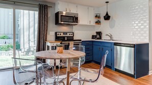 Cozinha moderna com armários brancos, micro-ondas de aço inoxidável, lava-louças e bancada azul.