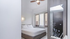A bedroom with a bed, a ceiling fan, a radiator, and a window with curtains. - Marina View Terrace by Wonderful Italy (Rapallo)