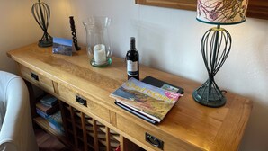 A wooden desk with two lamps, a candle, a bottle of wine, and a magazine. - 'Home From Home' 3 Bedroom Cottage in Nolton Haven (Haverfordwest)