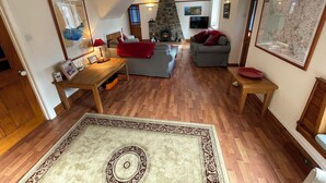 A cozy living room with a fireplace, a stone wall, and a large map on the wall. - 'Home From Home' 3 Bedroom Cottage in Nolton Haven (Haverfordwest)