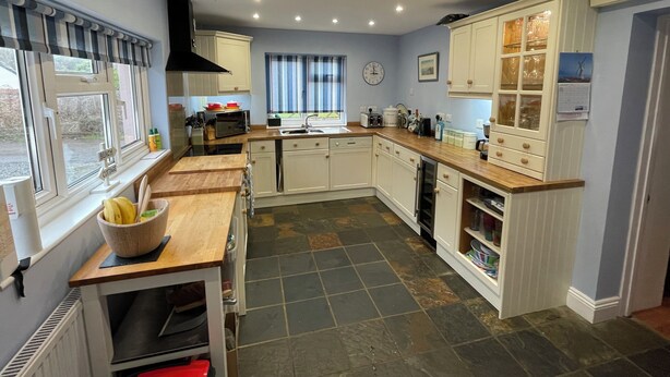 A modern kitchen with white cabinets, a wooden countertop, and a built-in dishwasher. - 'Home From Home' 3 Bedroom Cottage in Nolton Haven (Haverfordwest)