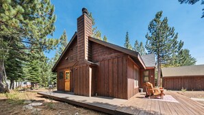 Une cabane en bois dotée d’un porche, entourée de pins.