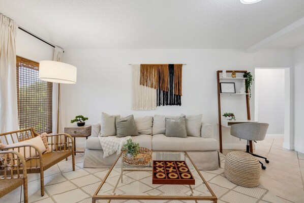 A living room with a sofa, a coffee table, a lamp, and a bookshelf.