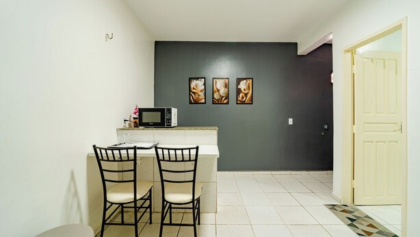 A small kitchen with a microwave, two chairs, and three framed pictures on the wall. - Flat Pet Friendly pr x ao Aeroporto (Fortaleza)