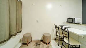 A small kitchenette with a microwave, a sink, and a dining area with two stools and a table. - Flat Pet Friendly pr x ao Aeroporto (Fortaleza)