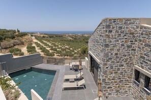 A stone building with a pool and outdoor seating area overlooking a coastal landscape. - Villa Dimitrios - With Private Pool (Rethymno)