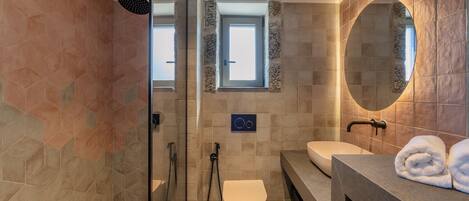 A modern bathroom with a glass shower enclosure, a toilet, a sink, and a vanity with a mirror.