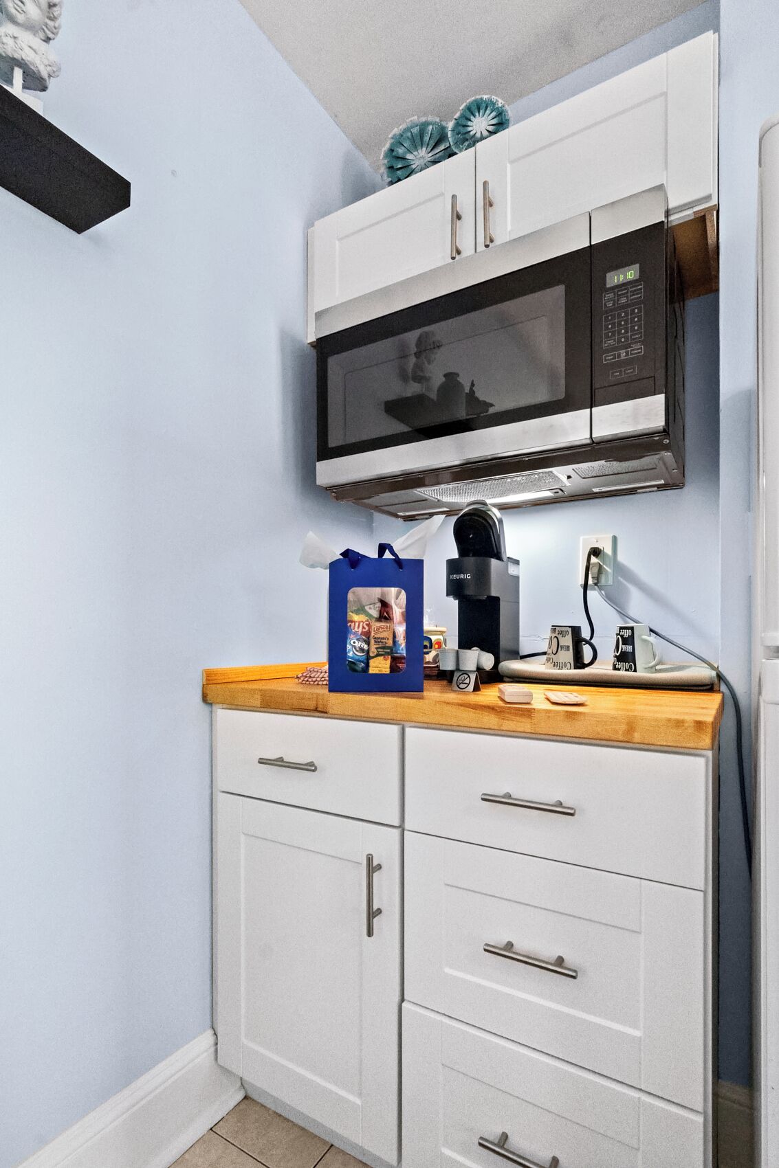 Una kitchenette compacta con microondas, cafetera y un pequeño armario.