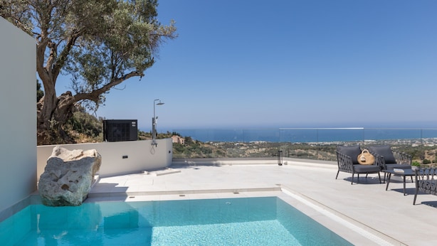 A swimming pool with a view of the sea, outdoor furniture, and a large rock. - Villa Santa Irini 3 - With Heated Pool (Rethymno)