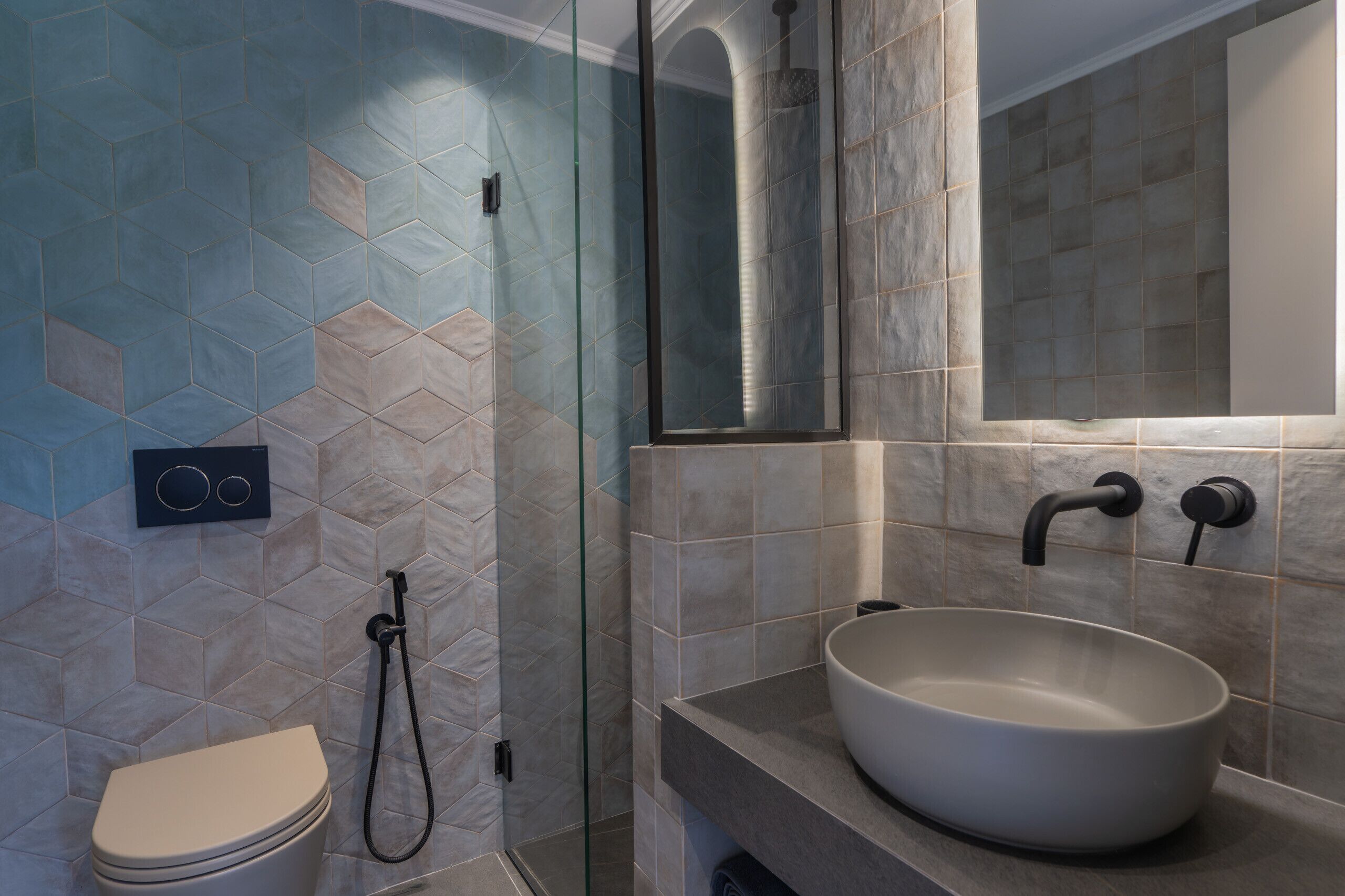 A bathroom with a toilet, a glass-enclosed shower, and a sink with a mirror above it.
