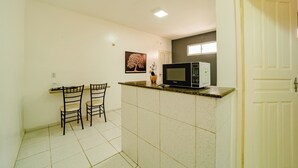 A compact kitchen with a microwave, two chairs, and a small table. - Flat Para 2 Pessoas a Poucos Metros do Aeroporto (Fortaleza)