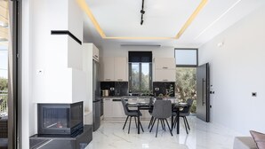 A modern kitchen with a dining area, large windows, and a fireplace. - Villa Me - With Private Pool (Mylopotamos)