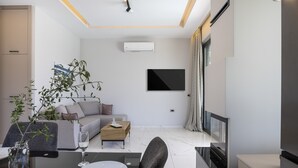 A modern living room with a sofa, coffee table, and a TV mounted on the wall. - Villa Me - With Private Pool (Mylopotamos)