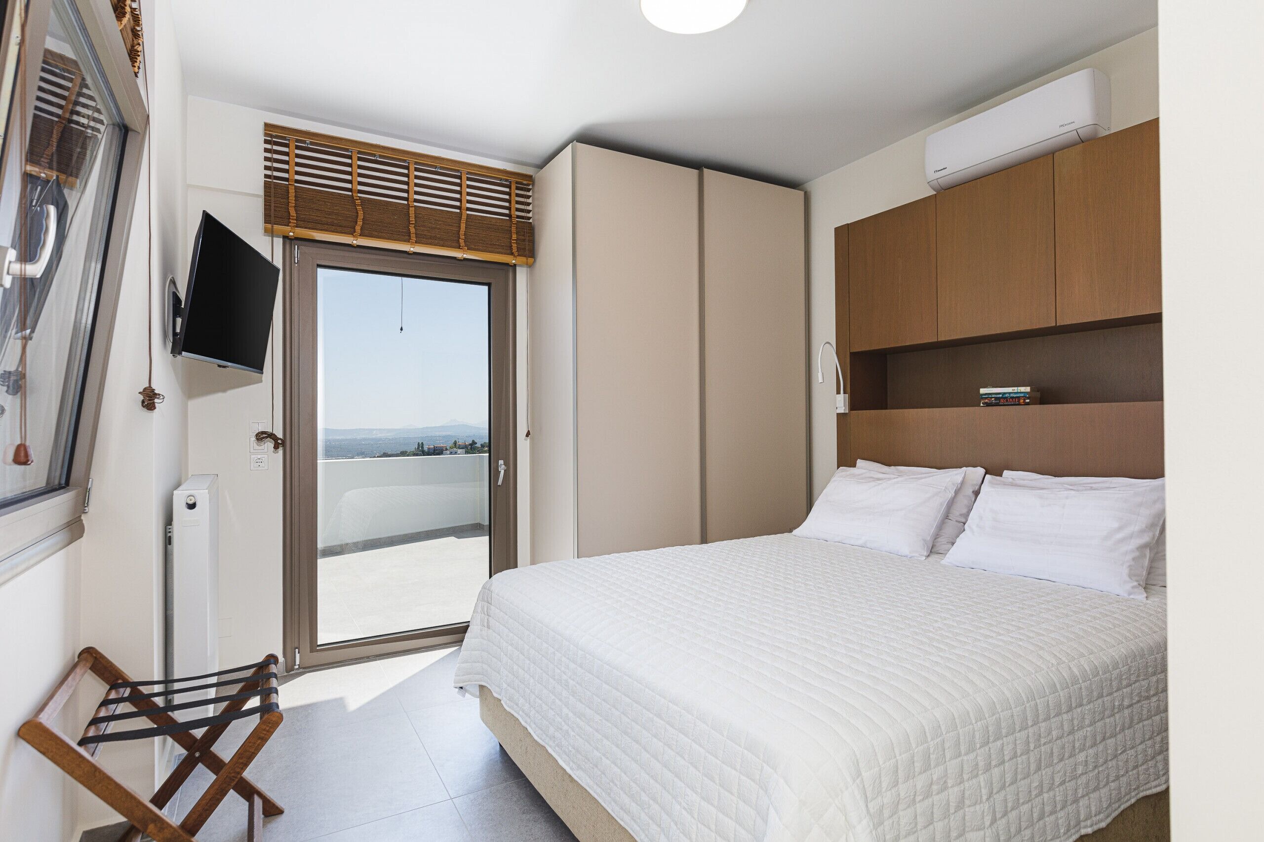 A bedroom with a bed, a television, a window, and a wardrobe.