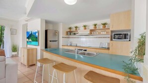 Une cuisine moderne dotée d’un coin bar, d’un réfrigérateur, d’un four à micro-ondes et d’un téléviseur.
