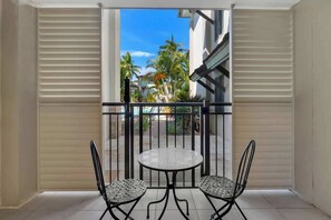 Un balcone con un tavolino rotondo e due sedie, vista su palme e un edificio.