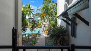 Vue d’une piscine entourée de palmiers, avec un ciel dégagé.